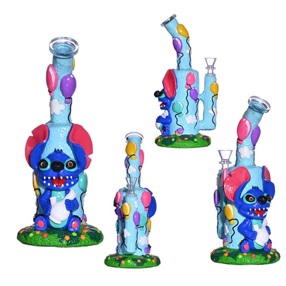 Four views of a decorative glass water pipe featuring a blue cartoon character with red ears, colorful balloon motifs, and a green grass-like base, shown on a plain white background.